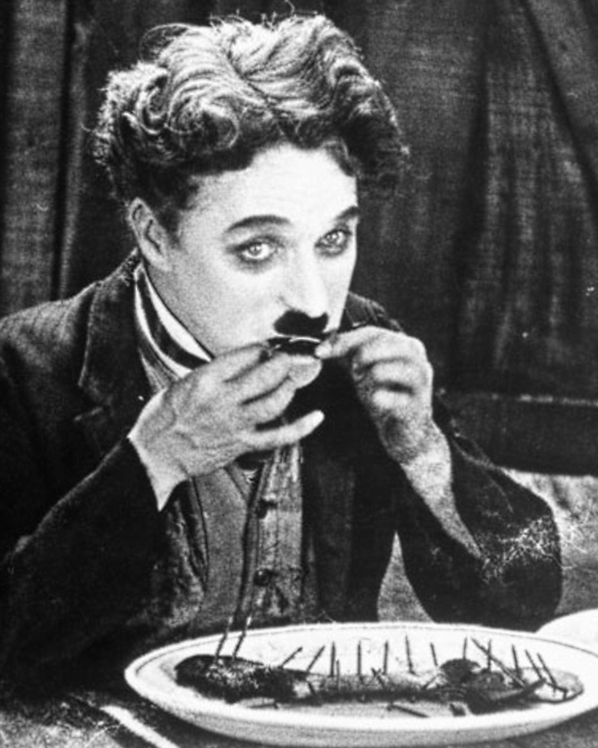 Charlie Chaplin eating a boot in a publicity still for The Gold Rush