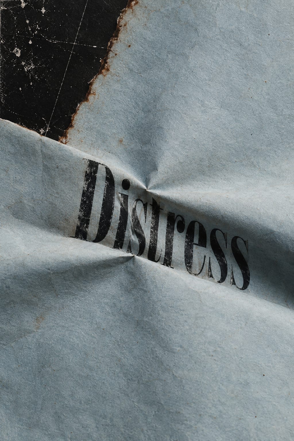 The word Distress is compressed into a deep fold in pale blue-grey paper.
